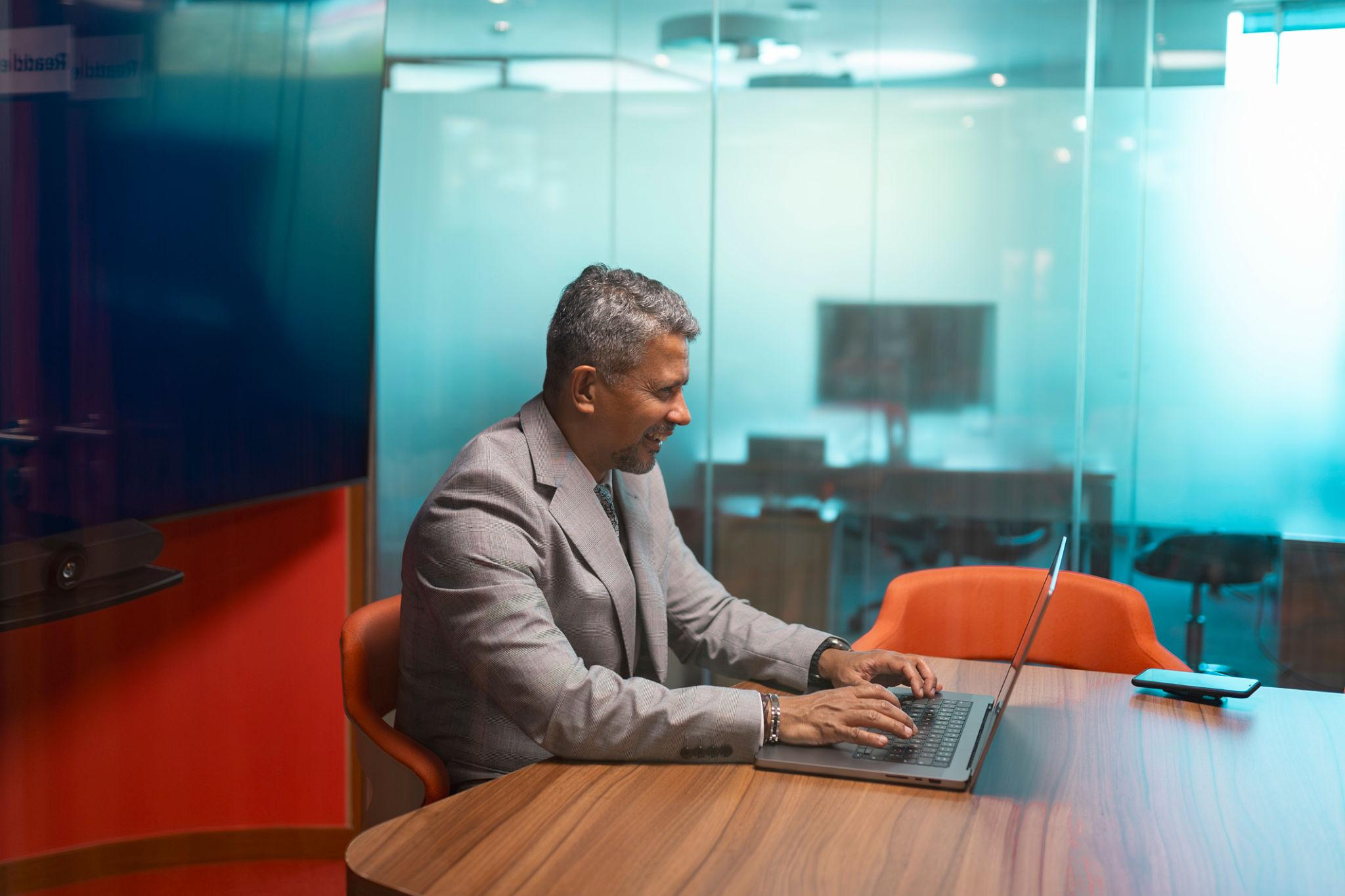 Professional working in a glass office with natural daylight and outdoor views.png